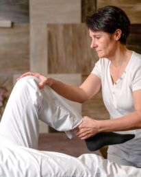 Eine Masseurin dehnt das Bein des Kunden