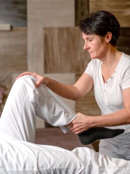 Eine Masseurin dehnt das Bein des Kunden