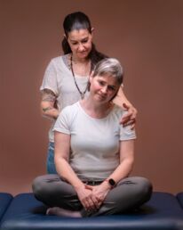 Eine Frau wird im Sitzen am Rücken massiert