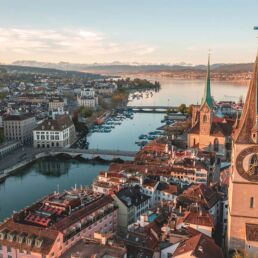 Massagekurier - Massage Z&uuml;rich - Luftaufnahme von Z&uuml;rich mit Limmat, See, Altstadt und Alpenpanorama bei Sonnenuntergang