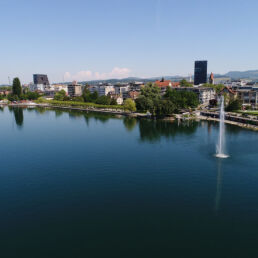 Massagekurier - Massage Zug - Luftaufnahme von vom Zugersee mit Blick auf die Stadt Zug mit dem Springbrunnen